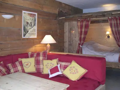 a living room with a red couch and a bed at Studio Les Drus / Studio du Brévent in Chamonix-Mont-Blanc