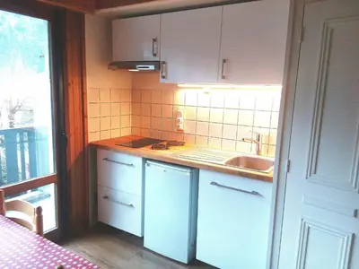 a kitchen with white cabinets and a sink next to a window at Studio Les Drus / Studio du Brévent in Chamonix-Mont-Blanc