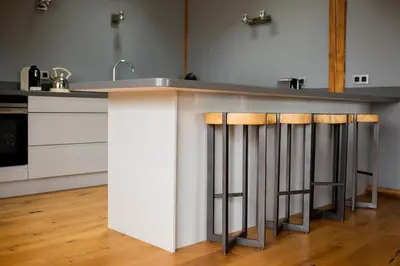 a kitchen with a counter with three bar stools at Chalet Byram in Saint-Gervais-les-Bains