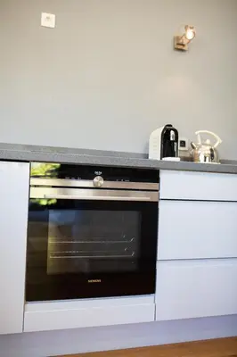 a kitchen with a black oven and white cabinets at Chalet Byram in Saint-Gervais-les-Bains