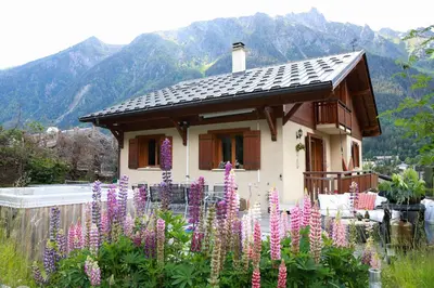 a small house with purple flowers in front of it at Chamonix Large Chalet, Sleeps 12, 200m2, 5 Bedroom, 4 Bathroom, Garden, Jacuzzi, Sauna in Chamonix-Mont-Blanc
