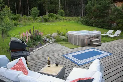 a patio with a hot tub and a grill at Chamonix Large Chalet, Sleeps 12, 200m2, 5 Bedroom, 4 Bathroom, Garden, Jacuzzi, Sauna in Chamonix-Mont-Blanc