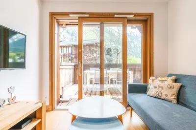 a living room with a blue couch and a table at Apt. Grand Paradis B14 - Modern with Mont Blanc view in Chamonix-Mont-Blanc