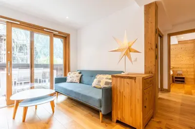 a living room with a blue couch and a table at Apt. Grand Paradis B14 - Modern with Mont Blanc view in Chamonix-Mont-Blanc