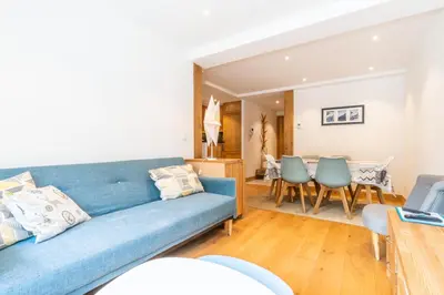 a living room with a blue couch and a dining room at Apt. Grand Paradis B14 - Modern with Mont Blanc view in Chamonix-Mont-Blanc