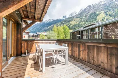a wooden balcony with a white table and chairs at Apt. Grand Paradis B14 - Modern with Mont Blanc view in Chamonix-Mont-Blanc