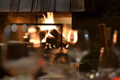 a fireplace with a person sitting in front of it at Chalet Hôtel du Bois in Les Houches