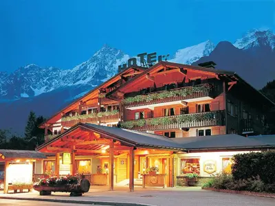 a large building with mountains in the background at Chalet Hôtel du Bois in Les Houches