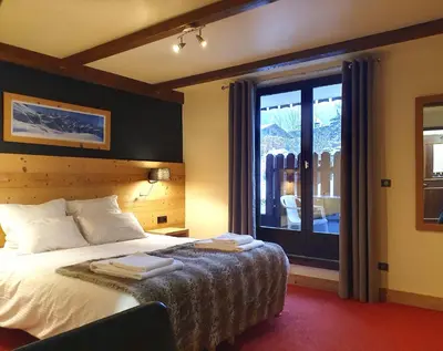 a hotel room with a bed and a large window at Chalet Hôtel du Bois in Les Houches