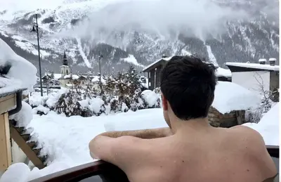 a man sitting on a balcony looking at a snow covered mountain at 