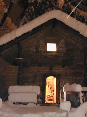 a cabin with snow on the roof and a window at 