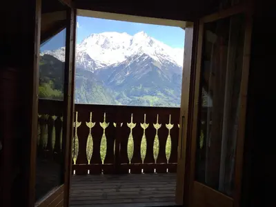 a view of a snow covered mountain through a door at Chalet du Meilly in Saint-Gervais-les-Bains
