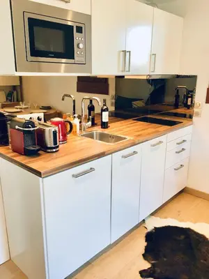 a kitchen with white cabinets and a sink at Appartement cosy et chaleureux à Megève avec vue sur le Mont Blanc in Demi-Quartier