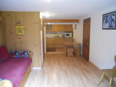 a living room with a red couch and a kitchen at Chalets Pyrene Mont-Blanc in Chamonix-Mont-Blanc