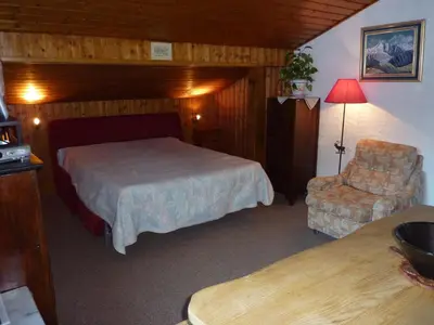 a bedroom with a bed and a chair in a room at Chalets Pyrene Mont-Blanc in Chamonix-Mont-Blanc