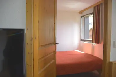 a small bedroom with a bed and a wooden door at Appt 4 /5 pers - 3 min. centre ville in Chamonix-Mont-Blanc