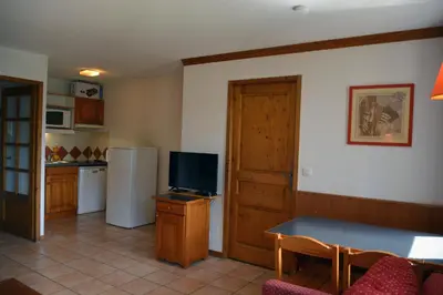 a living room with a television and a kitchen at Appt 4 /5 pers - 3 min. centre ville in Chamonix-Mont-Blanc