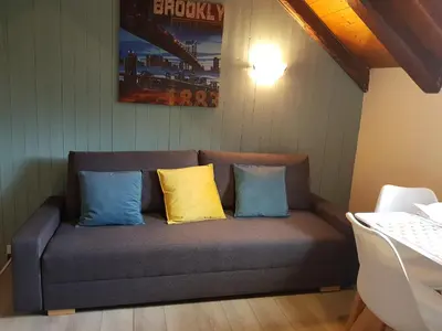 a couch with two blue and yellow pillows on it at Studio Duplex Place de la Grenette in Sallanches