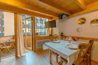 a dining room with a table and chairs and a television at Résidence Grand Roc - Campanules 322 - Happy Rentals in Chamonix-Mont-Blanc