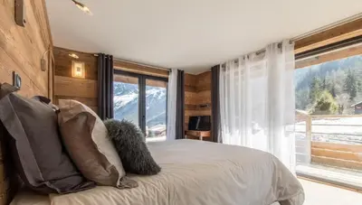 a bedroom with a bed and a large window at chalet des grands bois in Les Houches