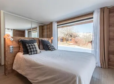 a bedroom with a large bed with a large window at chalet des grands bois in Les Houches