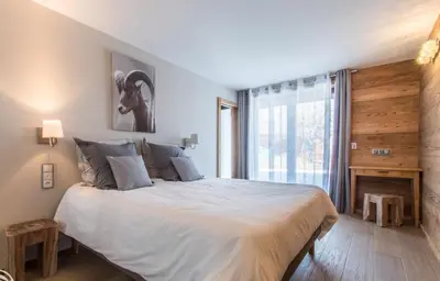 a bedroom with a large bed and a large window at chalet des grands bois in Les Houches