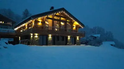 a lit up house in the snow at night at chalet des grands bois in Les Houches