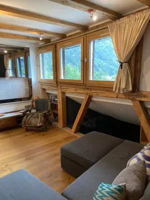 a living room with a couch and a tv and windows at Beautiful apartment in Chamonix centre with superb mountain views in Chamonix-Mont-Blanc
