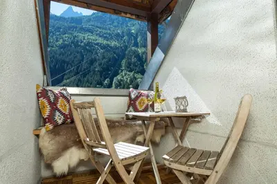 a table and chairs on a balcony with a view at Apartment Midi Loft - A Central Chamonix Mountain Haven in Chamonix-Mont-Blanc