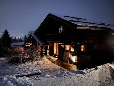 a log cabin in the snow at night at Chambres et Mazots du Chalet de Mado in Megève