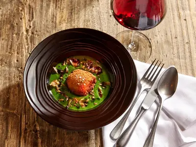a bowl of food on a table next to a glass of wine at Hôtel L'Arboisie in Megève