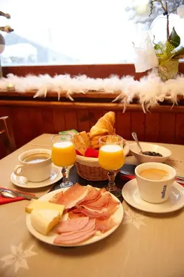 a table with a plate of food and glasses of orange juice at La Gelinotte in Les Contamines-Montjoie