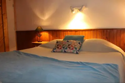a bed with a pillow and a light on the wall at La Gelinotte in Les Contamines-Montjoie