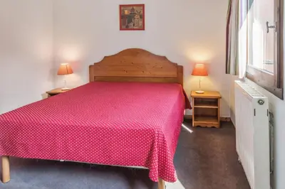 a bedroom with a red bed with two lamps on two tables at maeva Home Résidence la Rivière in Chamonix-Mont-Blanc