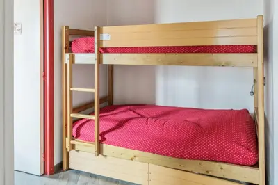 two bunk beds in a room with red sheets at maeva Home Résidence la Rivière in Chamonix-Mont-Blanc