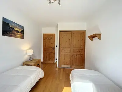 a bedroom with two beds and wooden doors at Appartement T3 au Centre de Chamonix avec WIFI et Parking - FR-1-507-3 in Chamonix-Mont-Blanc