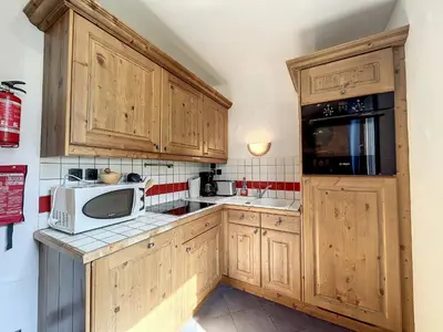 a kitchen with wooden cabinets and a microwave at Appartement T3 au Centre de Chamonix avec WIFI et Parking - FR-1-507-3 in Chamonix-Mont-Blanc