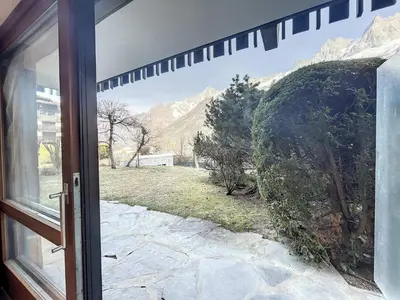 a door to a window with a view of a yard at Appartement Chaleureux à Chamonix, 4 Pers, Près du Brévent avec Terrasse et Parking - FR-1-507-26 in Chamonix-Mont-Blanc