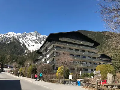 a large building with a mountain in the background at Appartement Chaleureux à Chamonix, 4 Pers, Près du Brévent avec Terrasse et Parking - FR-1-507-26 in Chamonix-Mont-Blanc