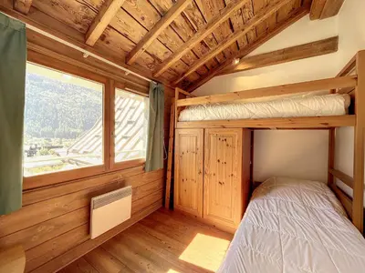 a bedroom with a bunk bed and a window at Chamonix: Appart. standing 6 pers, 3 ch, parking, centre-ville - FR-1-507-35 in Chamonix-Mont-Blanc