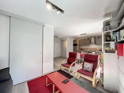 a living room with two chairs and a red table at Appartement rénové à Chamonix, balcon, parking - FR-1-507-37 in Chamonix-Mont-Blanc