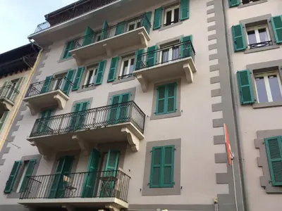 a tall white building with green shutters and balconies at Appartement rénové à Chamonix, balcon, parking - FR-1-507-37 in Chamonix-Mont-Blanc