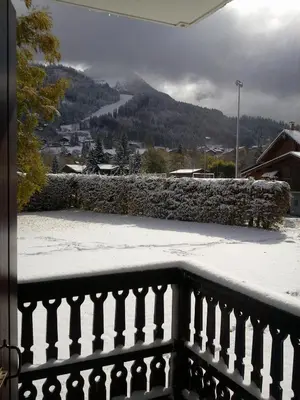 a balcony of a house with a green lawn and trees at Appartement les Carroz d'Arraches in Les Carroz d'Araches