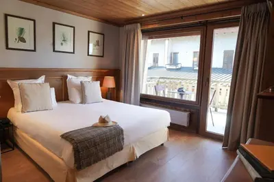 a bedroom with a large bed and a large window at Au Vieux Moulin in Megève