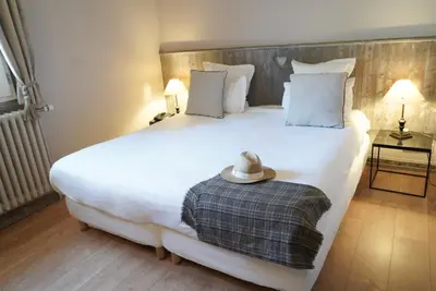 a bedroom with a large white bed with a hat on it at Au Vieux Moulin in Megève