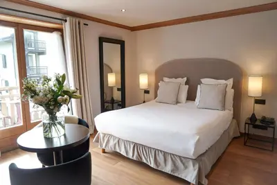 a bedroom with a bed and a table with a vase of flowers at Au Vieux Moulin in Megève