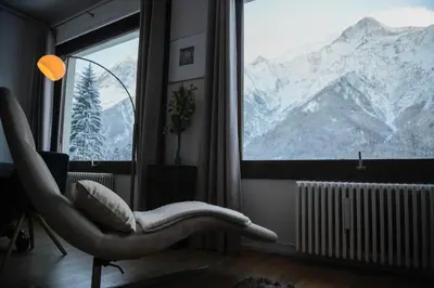 a room with a chair and a large window with mountains at Les Campanules in Les Houches