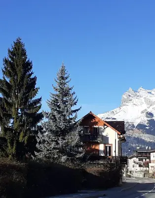 a house on the side of a road with a snow covered mountain at Hotel Val Joly in Saint-Gervais-les-Bains
