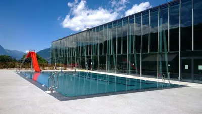 a swimming pool in front of a glass building at Hotel Val Joly in Saint-Gervais-les-Bains