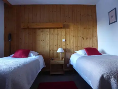 two beds in a room with wooden walls at Hotel Val Joly in Saint-Gervais-les-Bains